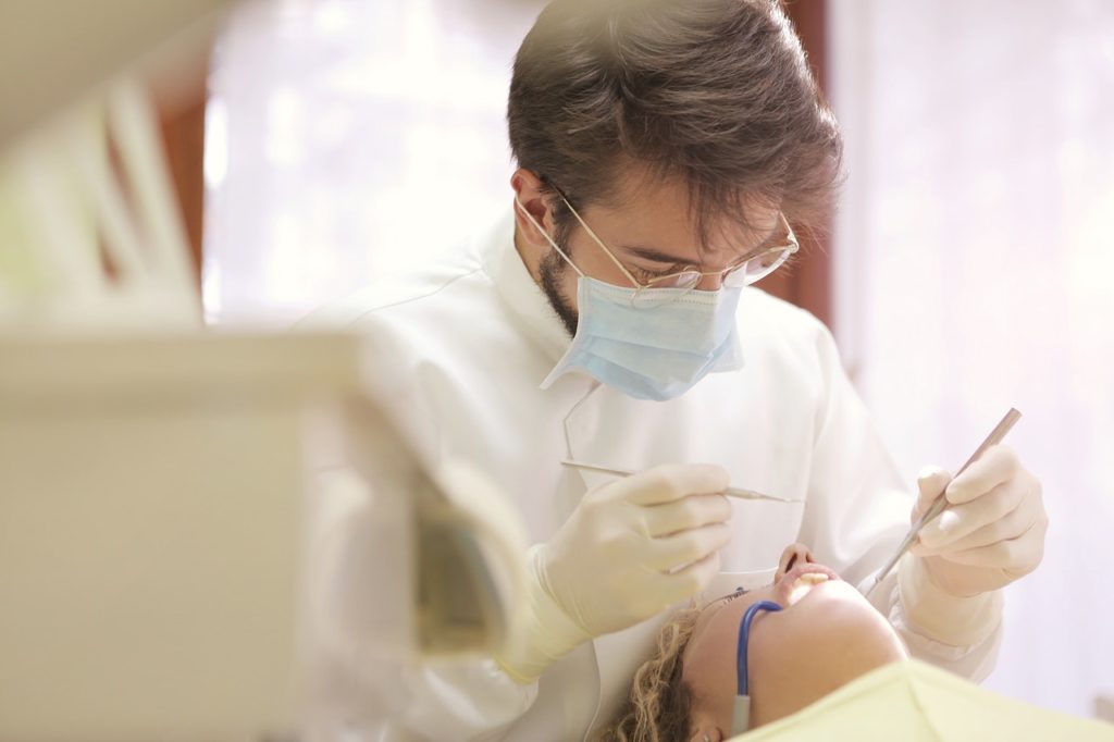 a male dentist checking a patient's teeth