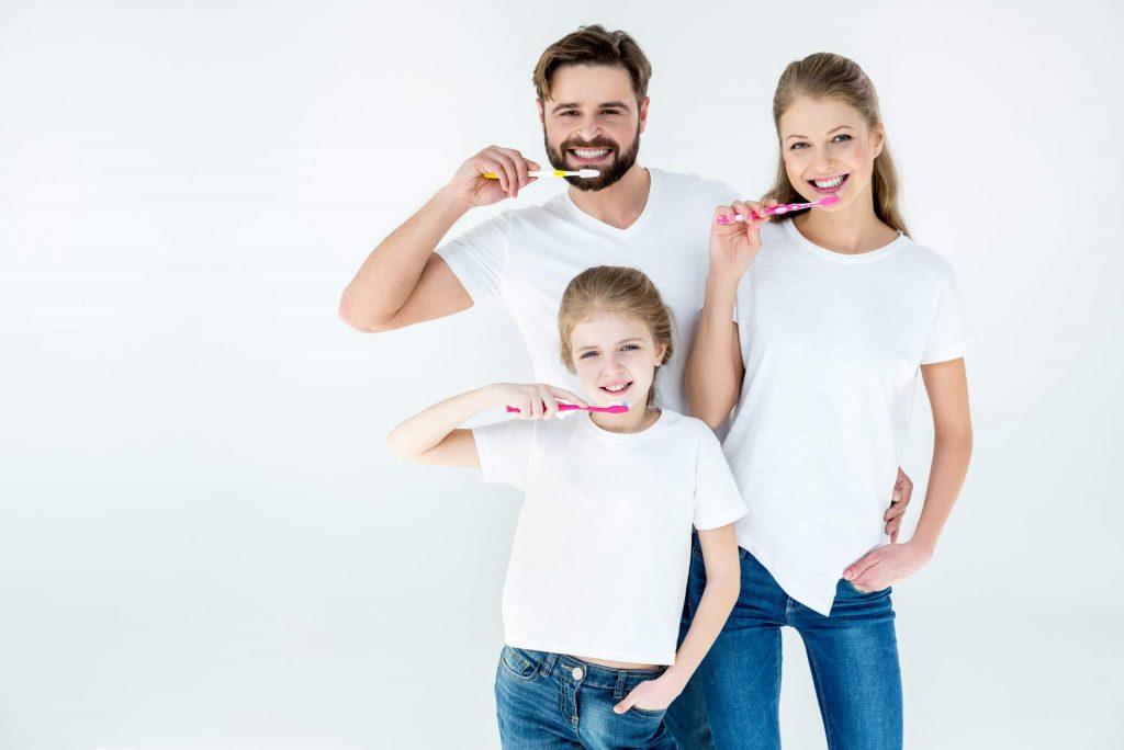 family holding toothbrushes