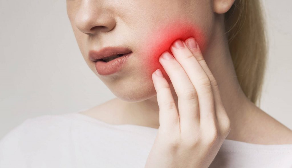 Woman suffering from toothache, touching inflamed cheek