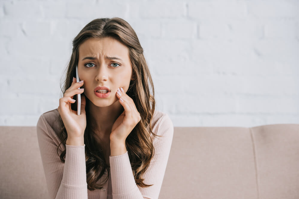 woman with tooth pain using a smartphone